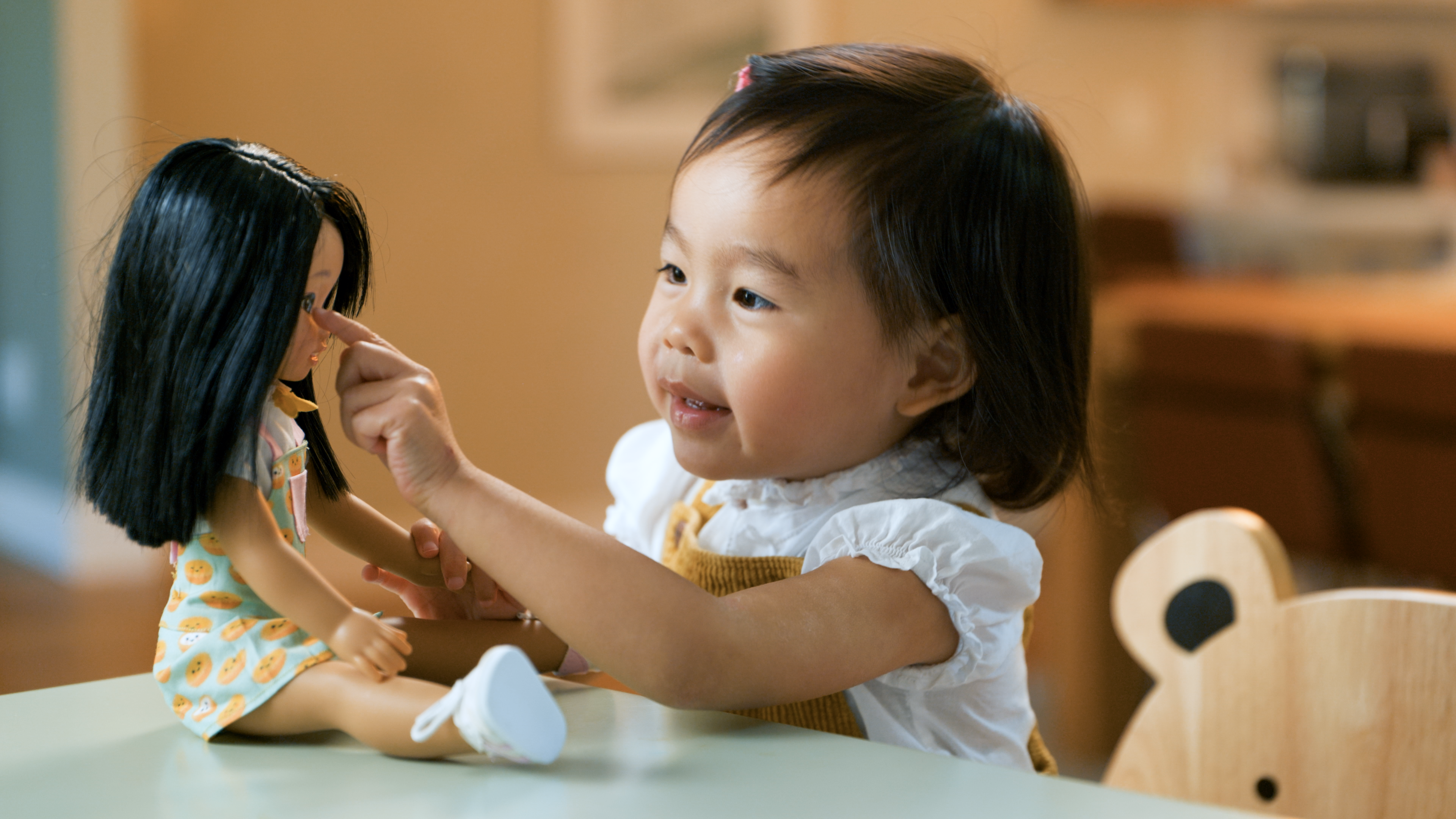 An Asian-American girl touching a doll's face