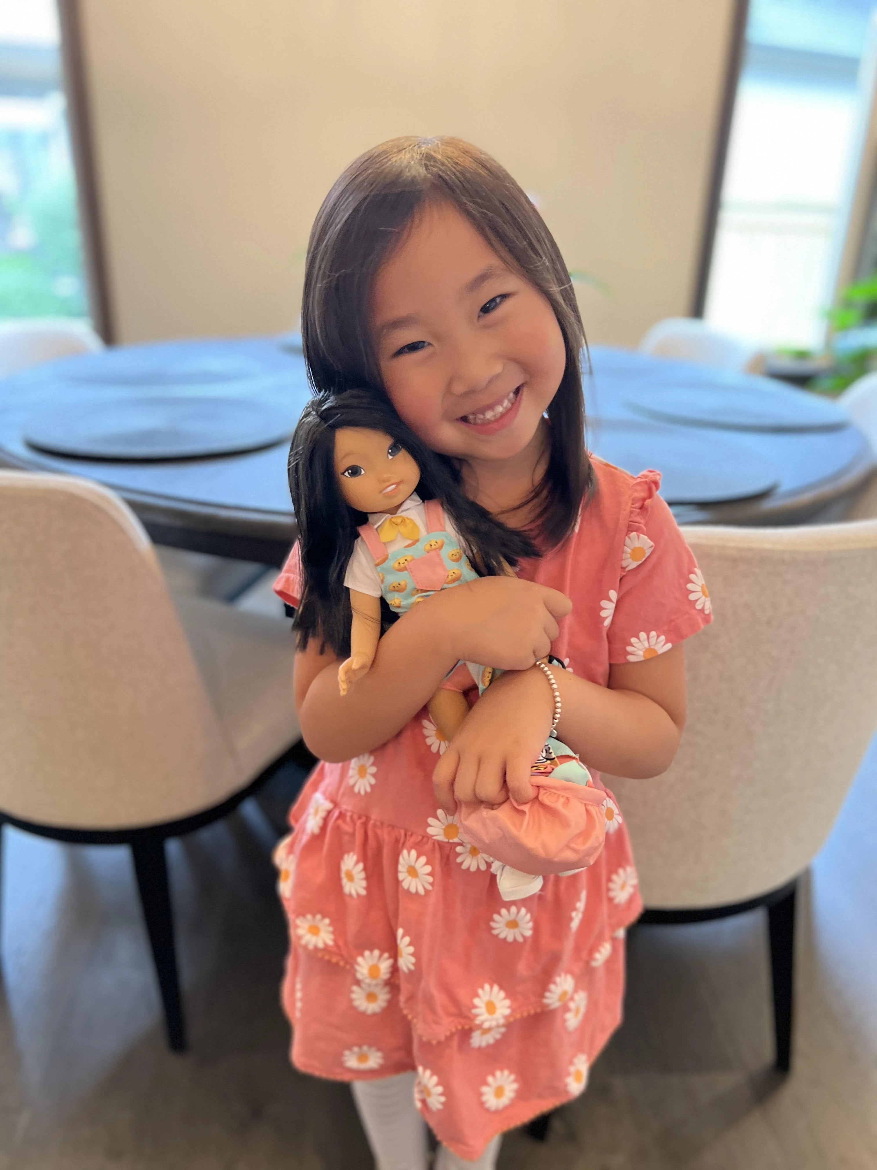 An Asian girl smiling while holding a Jilly doll