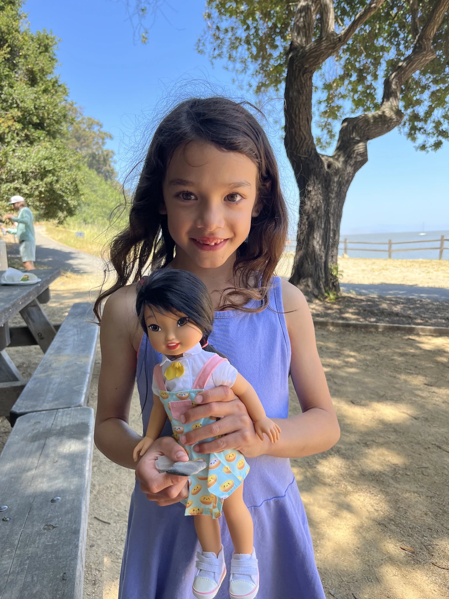A smiling girl holding a Jilly Bing doll outside
