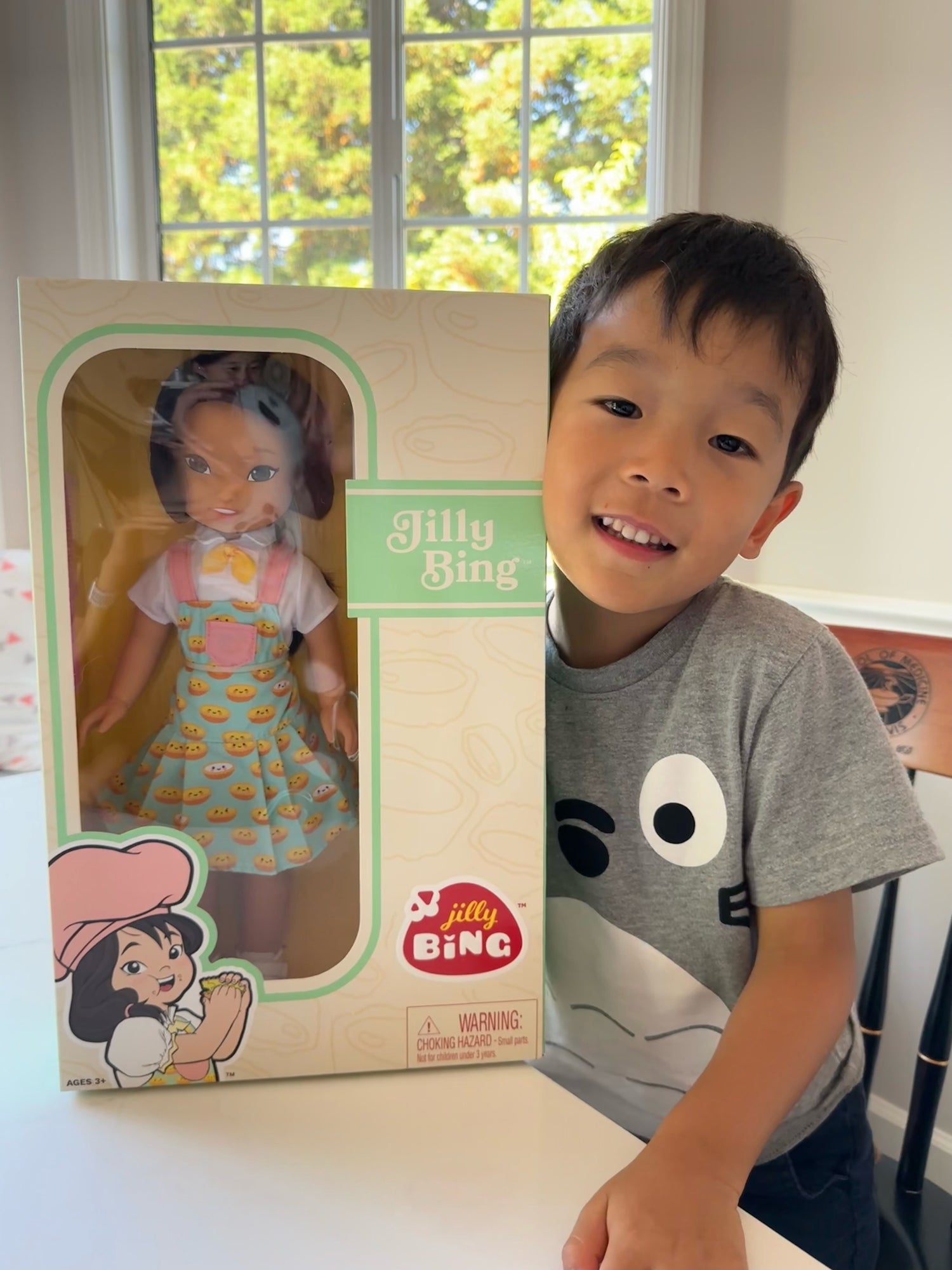A boy holding a Jilly Bing doll in the box