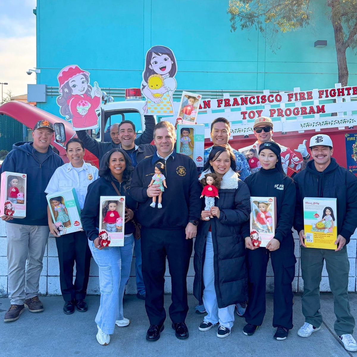 Jilly Bing and San Francisco firefighters holding Jilly Bing 14-inch dolls for the firefighter toy donation program supporting underserved children.